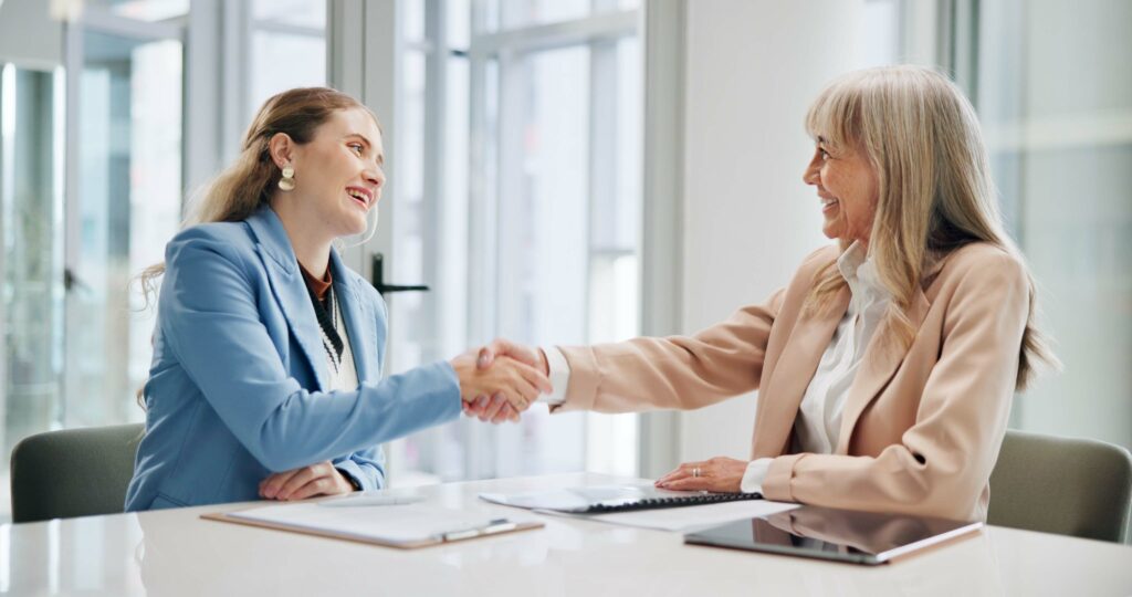 A female candidate shaking hands with a recruiter, accepting her first marketing job.
