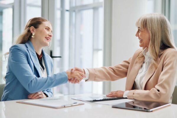 A female candidate shaking hands with a recruiter, accepting her first marketing job.