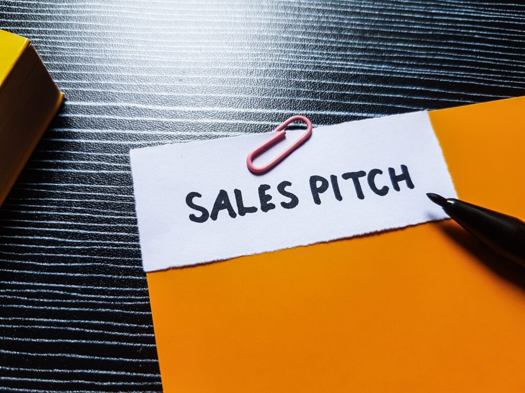 A paper with the words ‘Sales Pitch’ pinned against a colored sheet.