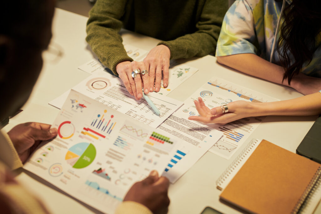 Three people reviewing charts and graphs from their market research.